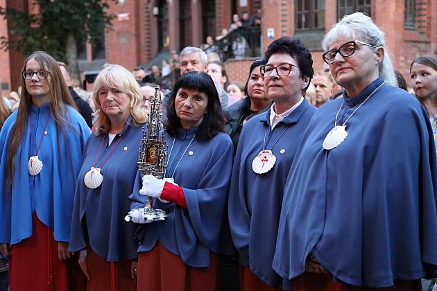 Uczestnicy Jarmarku św. Jakuba w niebieskich strojach z emblematami, uważnie patrzący.