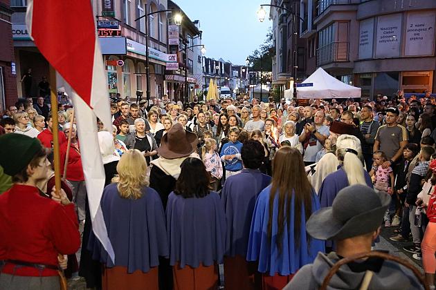 Pochód ludzi w niebieskich pelerynach i z flagami na Jarmarku św. Jakuba.