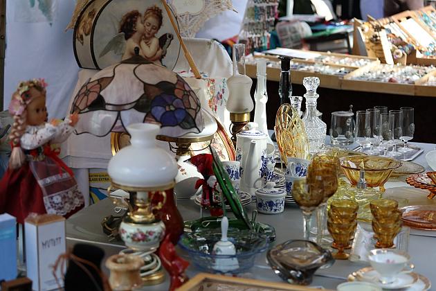 Stoisko z zabytkowym szkłem, ceramiką i ozdobami na jarmarku.