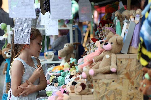 Dziewczynka ogląda kolorowe maskotki na stoisku podczas Jarmarku św. Jakuba.