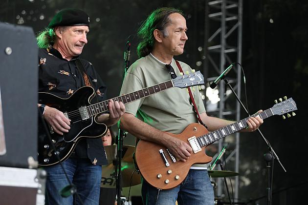 Dwaj gitarzyści grają na scenie podczas koncertu.