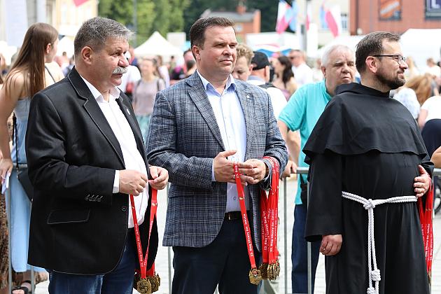 Dwaj mężczyźni w marynarkach i franciszkanin na Jarmarku św. Jakuba.