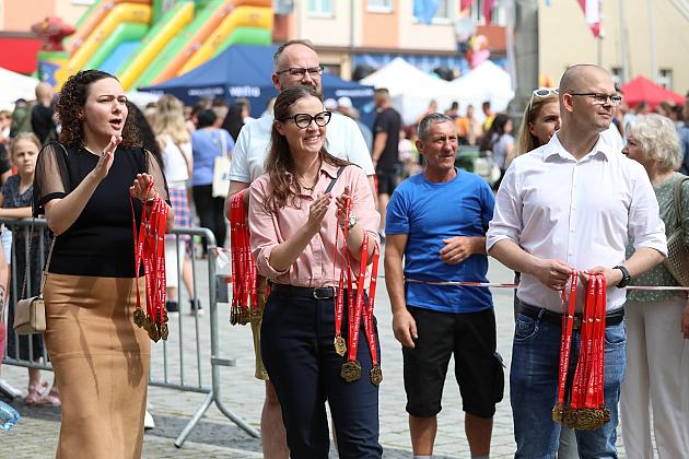Ludzie klaszczą i trzymają czerwone wstęgi na Jarmarku św. Jakuba.