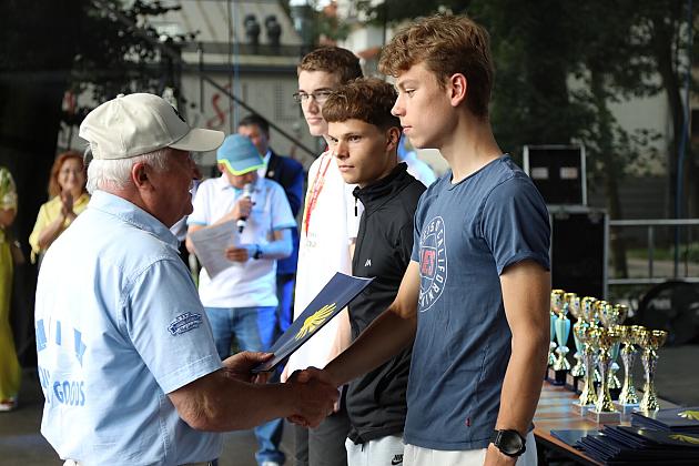 Starszy mężczyzna wręcza nagrody młodym uczestnikom Jarmarku św. Jakuba.