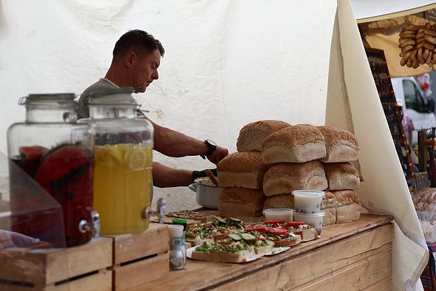 Sprzedawca obsługuje stoisko z chlebem i napojami na jarmarku św. Jakuba.