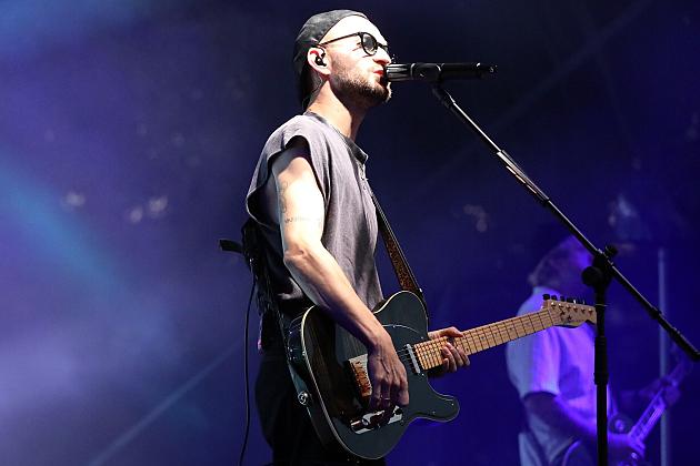 Muzyk gra na gitarze i śpiewa podczas koncertu na Jarmarku św. Jakuba.