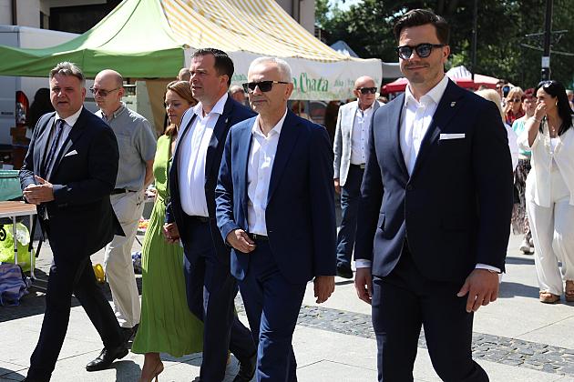 Grupa elegancko ubranych osób spaceruje na Jarmarku św. Jakuba.