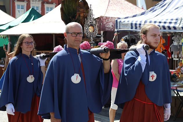 Ludzie w niebieskich pelerynach z muszlą św. Jakuba na jarmarku.