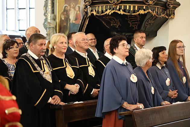 Grupa ludzi w strojach ceremonialnych podczas uroczystości w kościele.